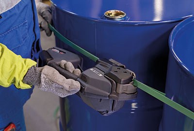 man applying strapping to large metal drum using automatic strapping tool