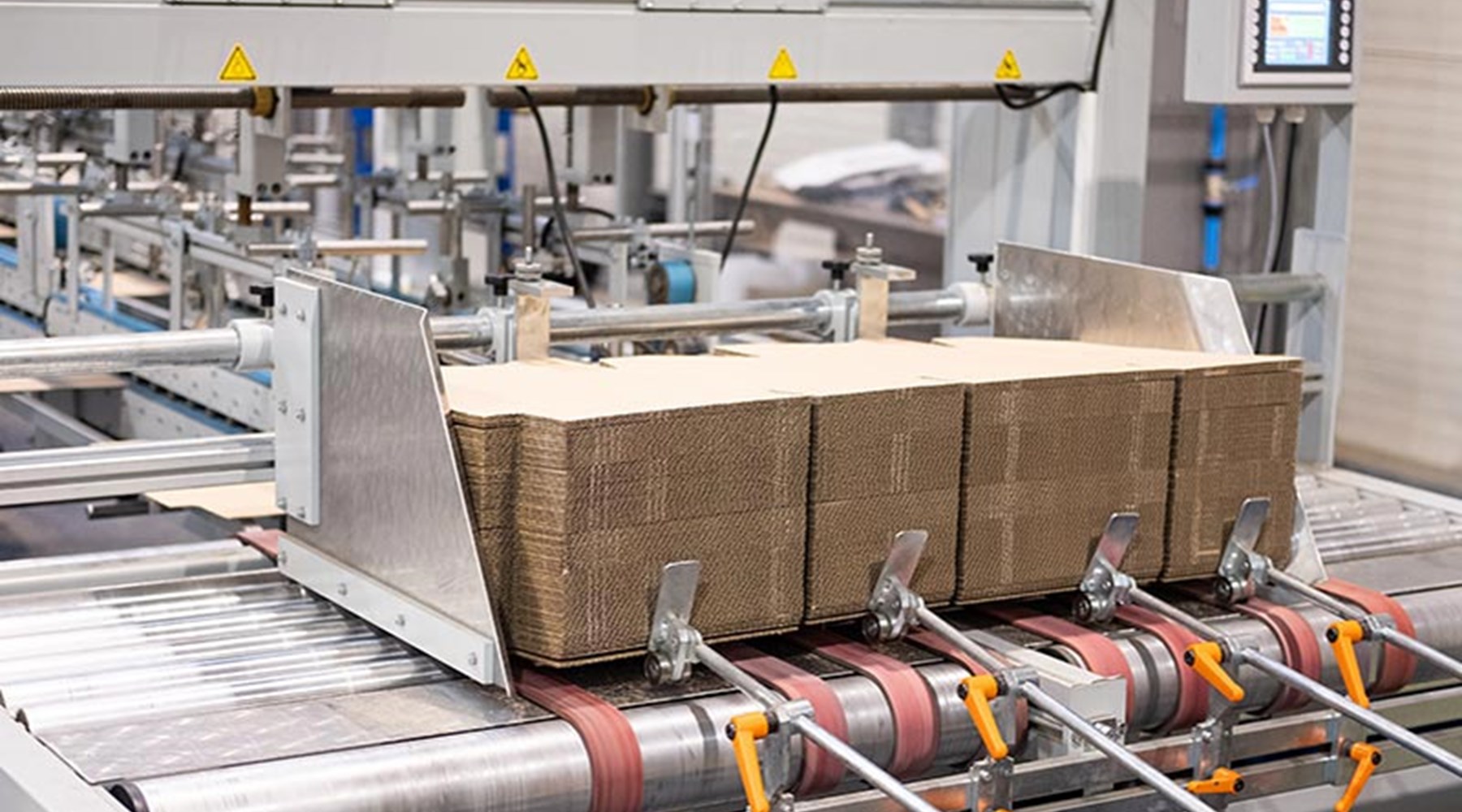 large pile of boxes loaded onto folder gluer machine